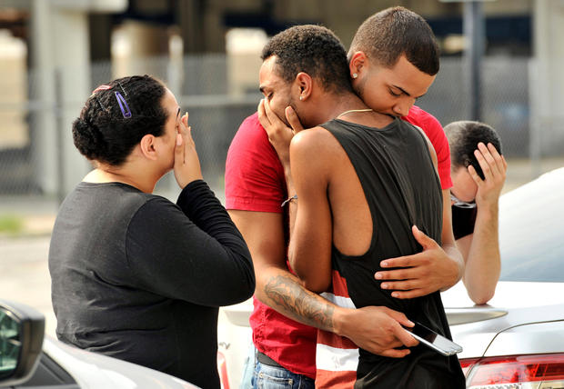 Friends and family members embrace outside the Orlando Police Headquarters during the investigation of a shooting at the Pulse night club in Orlando, Florida